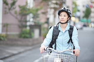 ヘルメット着用で自転車に乗る女性